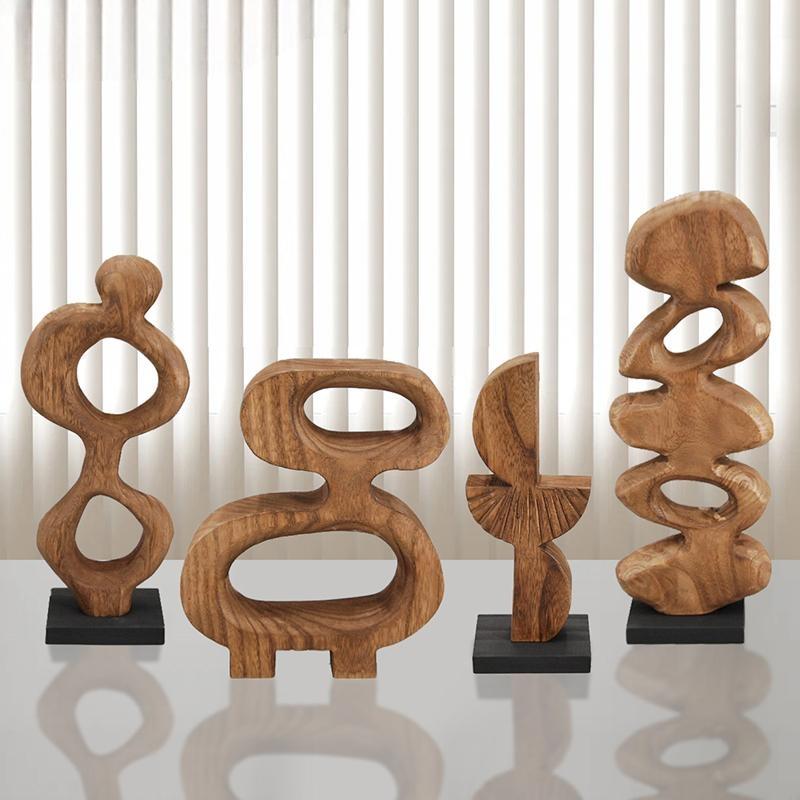 Four Geometric Solid Wood Wall Sculptures for the living room, each with a unique abstract design and organic shape, are displayed on black bases in front of vertical white blinds atop a reflective surface.