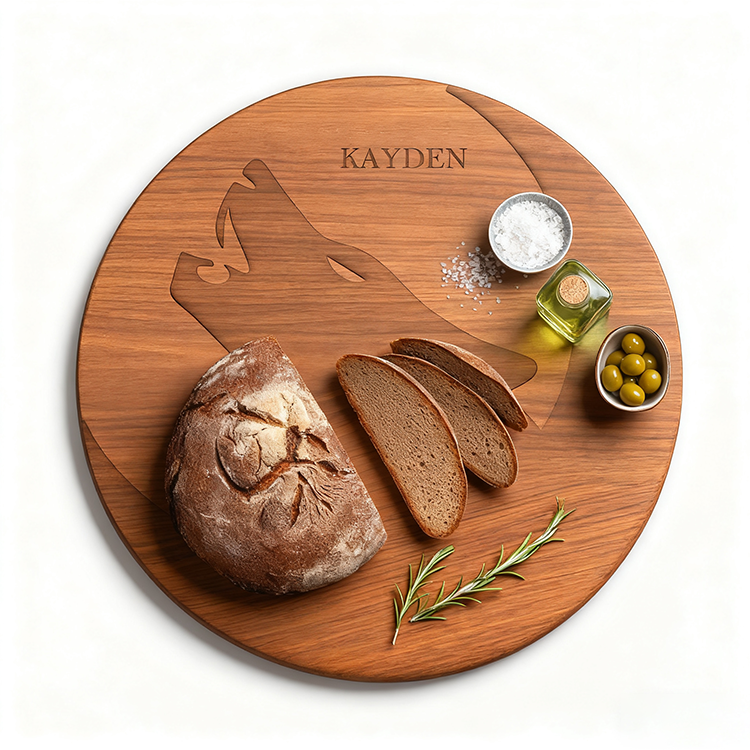The Personalized Round Cutting Board, engraved with a wolf and the name KAYDEN, holds sliced bread, salt, olive oil, green olives, and rosemary—a unique charcuterie board for any occasion.