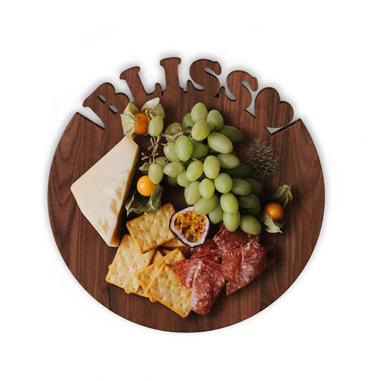 The Personalized Round Cutting Board features “BLISS” cut out at the top and is shown holding cheese, green grapes, crackers, cured meat slices, halved passion fruit, and golden berries—ideal for entertaining or as a unique wedding board.