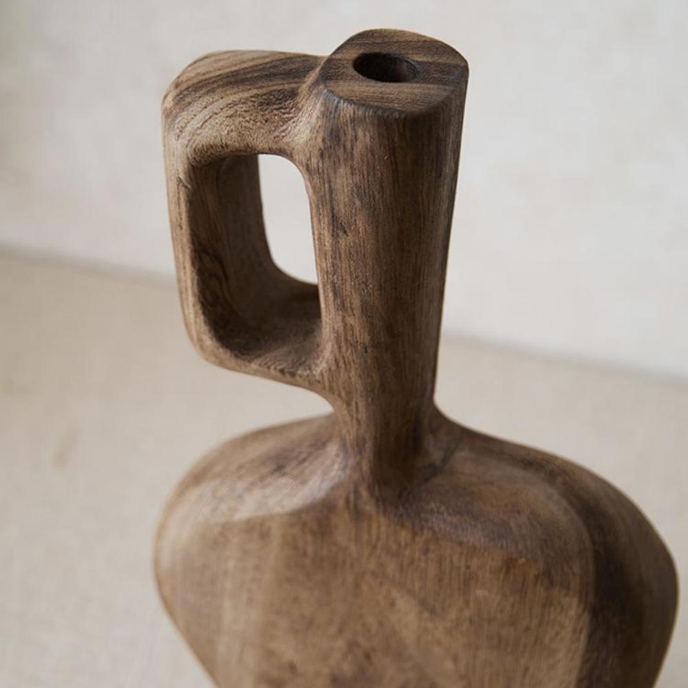 A close-up of the Tall Solid Wood Vase, Living Room 8×2.4×12.6 in, featuring smooth rounded edges and a hollow rectangular handle, standing upright on a beige surface.